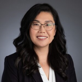 smiling woman with glasses in a black blazer